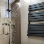 Электрический полотенцесушитель рядом с душевой кабиной